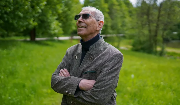 Hans Schneider steht im Grünen auf einer Wiese des Biohofs